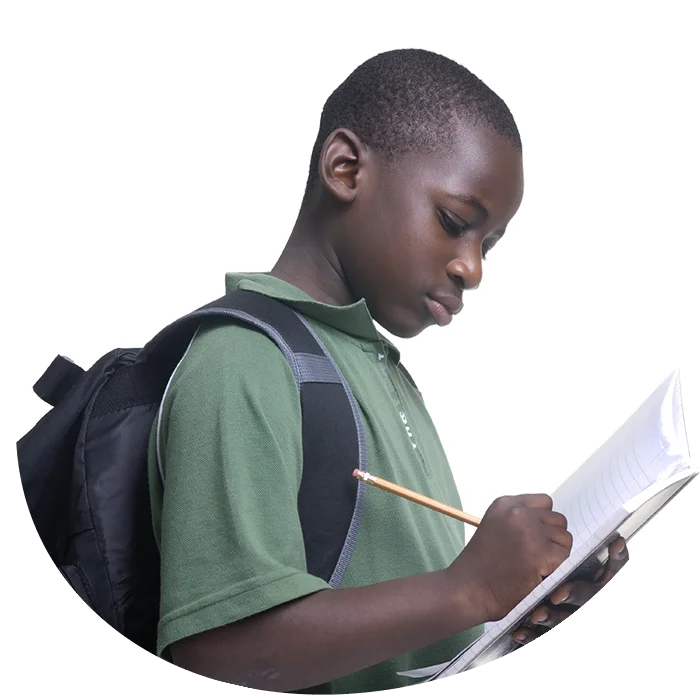 A boy is writing on paper with a backpack.