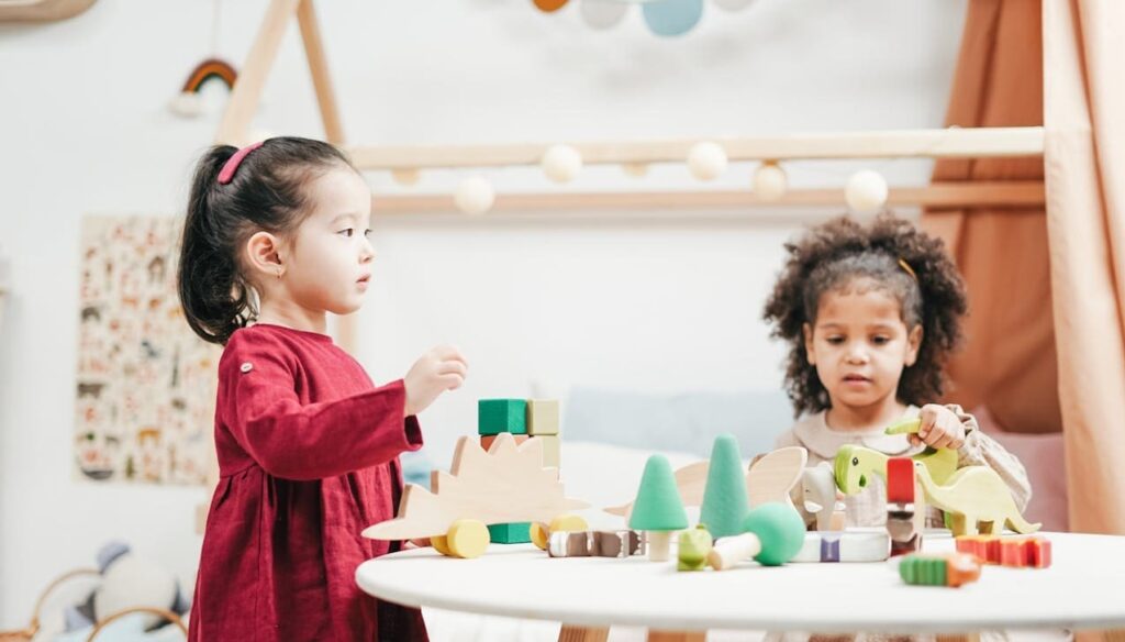 Two children engaging with wooden toys in a bright playroom. Ideal for education themes.